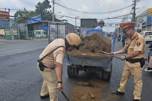 Nhớt tràn ra đường, CSGT TPHCM rải cát chống trượt dưới nắng nóng