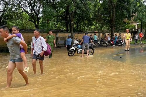 Công an huyện giúp dân di chuyển qua đoạn đường bị ngập do mưa lớn