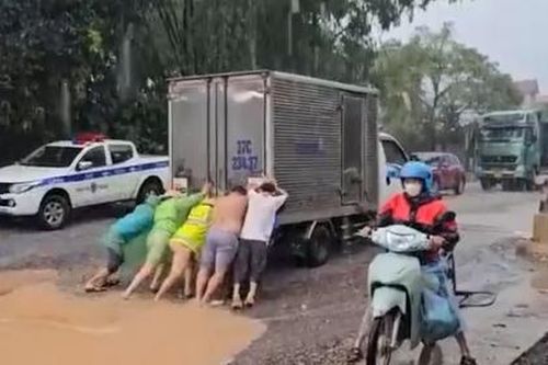 Cảnh sát giao thông dầm mình, giúp dân vượt qua điểm ngập lụt trong mưa lớn