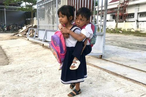 Cô bé 6 tuổi cõng bạn học liệt hai chân đến trường