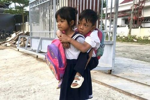 Cô bé 6 tuổi cõng bạn học liệt hai chân đến trường
