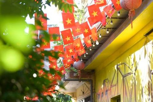 Cờ Tổ quốc rực rỡ trước cổng làng giữa phố phường Hà Nội