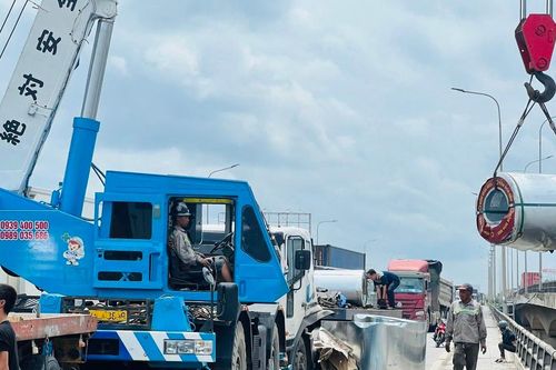 Xe đầu kéo phanh gấp, hàng chục tấn tôn cuộn rơi xuống quốc lộ 1