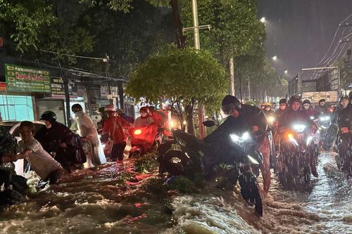 Mưa lớn kéo dài, người dân Đồng Nai 'vác xe' qua dải phân cách để thoát ngập