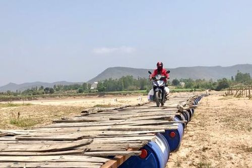 Chờ cầu xây mới, người dân lấy thùng phi ghép gỗ làm cầu tạm vượt sông Ba