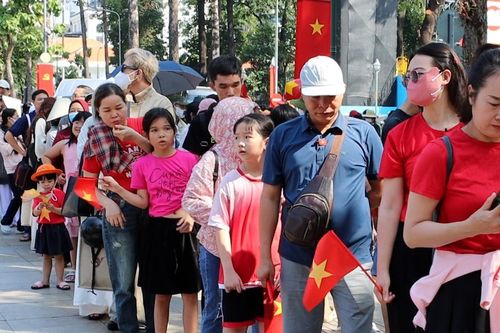 Người dân cầm cờ Tổ quốc, xếp hàng dài chờ tham quan Dinh Độc Lập trước lễ 30/4