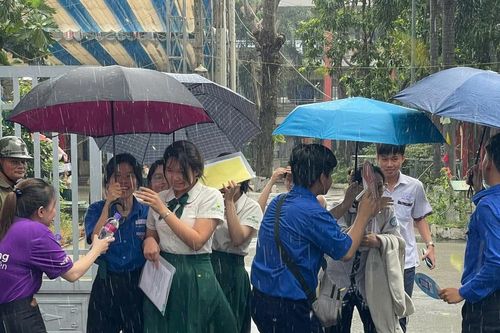 Tình nguyện viên đội mưa che ô cho thí sinh tại Bình Dương