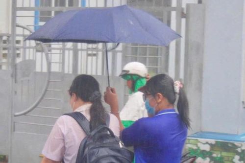 Tình nguyện viên che chắn cho thí sinh trong cơn mưa tầm tã