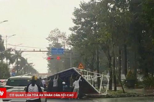 Tấm pano lớn bị gió cuốn bay đè lên người đi đường