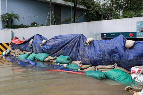 Ảnh hưởng bão số 10, đường phố Hà Nội ngập úng, người dân dùng bao cát chắn cửa