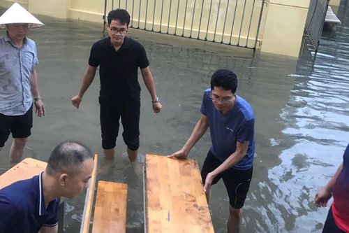 Hà Nội: Trường ngập nước, thầy cô kê bàn ghế làm đường cho phụ huynh đón con