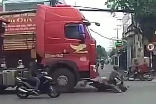 Người bán dừa đi xe máy thoát chết dù bị cuốn vào gầm container