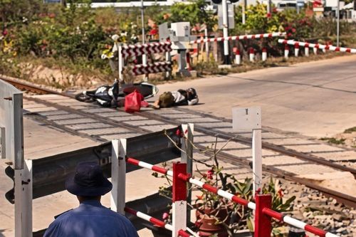 Người đi xe máy tông đổ rào chắn, ngã sát đường ray khi tàu đang đến