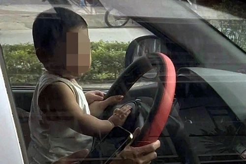 CSGT làm việc với nữ tài xế để trẻ nhỏ ngồi trước vô lăng ô tô đang chạy