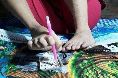 Cô gái khuyết tật dùng chân đính tranh đá thuần thục