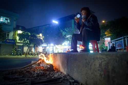 Người vô gia cư co ro đốt lửa, trùm chăn ngủ vỉa hè trong cái rét thấu xương