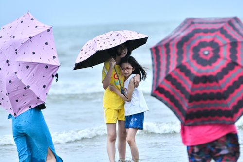 Che ô, mặc áo mưa tắm biển ở Sầm Sơn