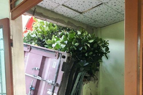 Thùng container lao khỏi xe đầu kéo, đâm sập tường nhà dân ven đường