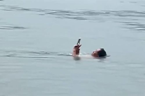 Người đàn ông vừa bơi vừa lướt điện thoại