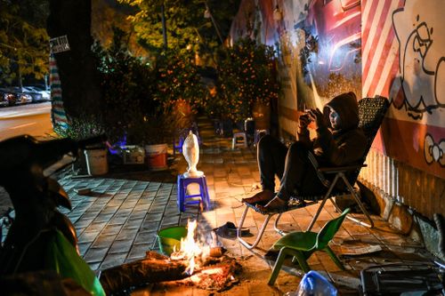 Tiểu thương đốt lửa sưởi ấm, trông đào Tết ngày Hà Nội rét đậm