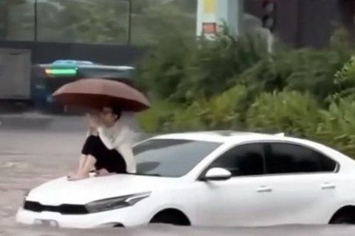Ung dung ngồi trên nắp capo ô tô bị ngập nước, người phụ nữ lý giải nguyên nhân