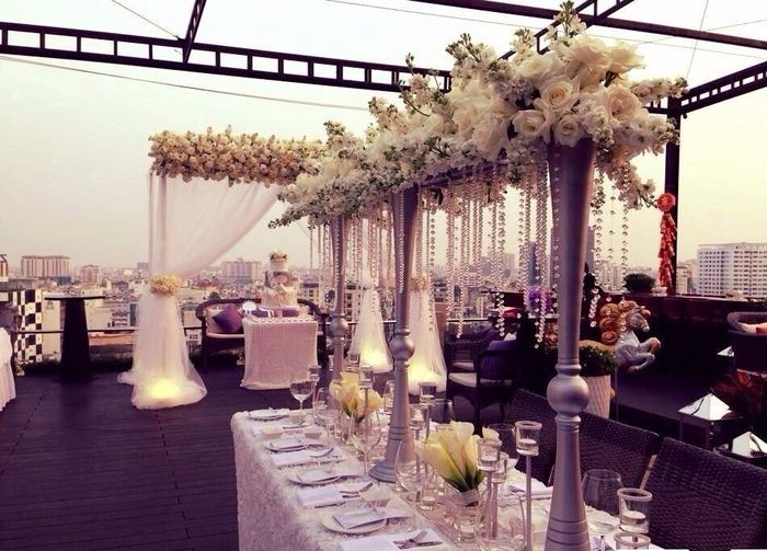  Trước giờ hôn lễ, khung cảnh cưới toàn sắc trắng cũng lộ diện với những đường đi với dải hoa trắng kèm dây pha lê trắng hai bên, ngoài bàn ghế trang trí, khăn trải màu trắng cùng tông, thì còn có sự xuất hiện của chiếc bánh cưới vô cùng hoành tráng và không kém lãng mạn.