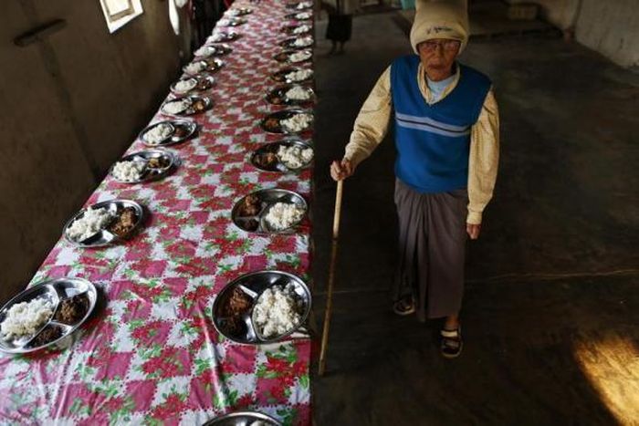 Một cụ ông đứng trong phòng ăn trong làng phong.