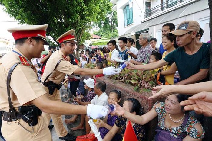 Cảnh sát chuyển nước uống cho người dân ngồi xem đoàn diễu binh trên phố Nguyễn Thái Học. Ảnh: Bá Đô/ VNE.