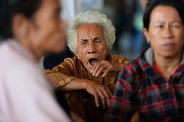  Một cụ bà ngáp dài vì chờ lâu .