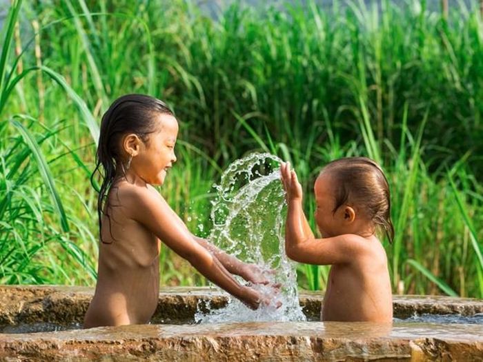 Hai chị em vừa tắm vừa nghịch nước. Ảnh: Phununews.