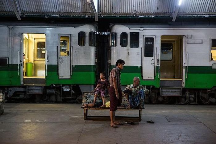 Một gia đình ngồi trên chiếc ghế dài cạnh đoàn tàu tại ga trung tâm Yangon.