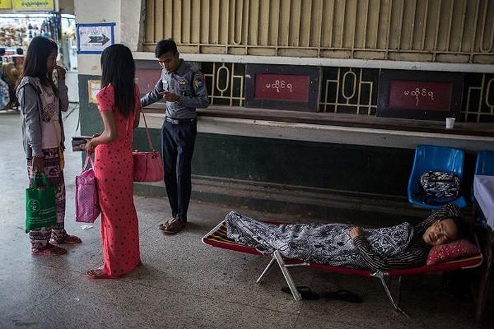 Một nhân viên nhà ga hướng dẫn hành khách trong khi người đồng nghiệp của anh tranh thủ chợp mắt sau ca làm đêm.