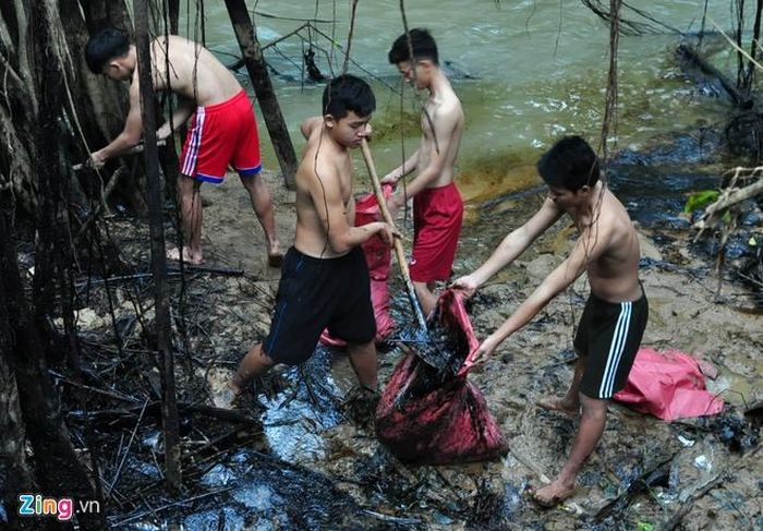 Cảnh sát cơ động mình trần thu gom dầu nhớt thải ven suối Lở chiều 17/12. Ảnh: Minh Hoàng.