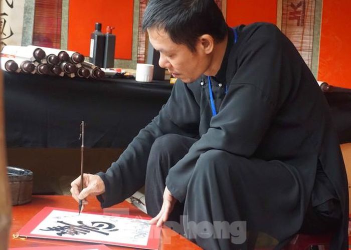 Thư họa gia Lê Quốc Việt, chủ khảo cuộc thi sát hạch ông đồ ở hội chữ cho biết hôm qua "trục xuất" hai ông đồ ngồi không đạt chuẩn ra khỏi lều chữ. Anh cũng là một trong những người cho chữ tỉ mỉ giải nghĩa cho người xin chữ. Ảnh: Nguyên Khánh
