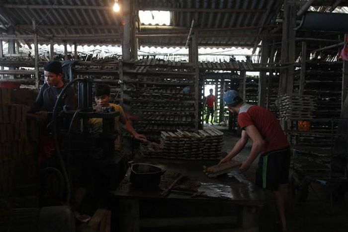 Công nhân ở đây phần lớn là người trong xã nhưng cũng không có ít thợ đến từ Diễn Châu, Nghĩa Đàn, Thanh Hóa… Trong cái mùi hăng hắc của dầu hỏa, tiếng ầm ầm của máy, một tốp công nhân đang đóng ngói thoăn thoắt. Theo như lời anh Hùng, thợ đóng gạch: “Bọn anh đóng gạch từ lúc 3 giờ sáng cho đến tận giờ. Điện đóm ở quê yếu lắm nên tranh thủ được lúc nào hay lúc đó”. Ảnh: An Viên