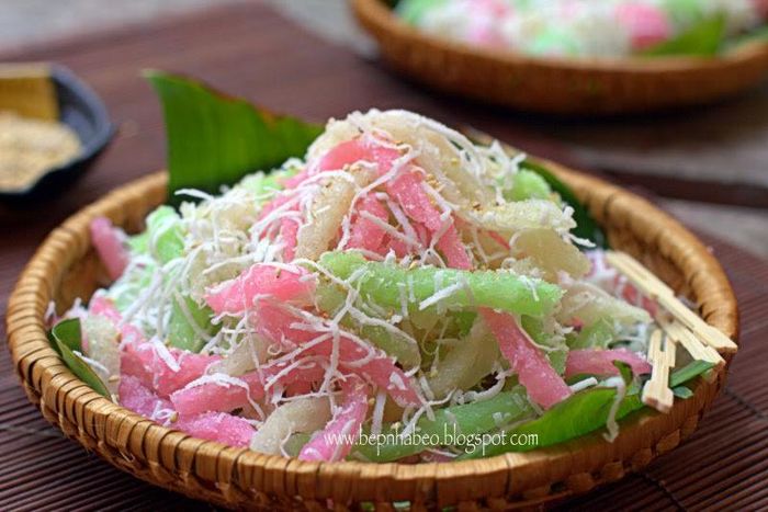 Hấp bánh: Khuôn thoa dầu ăn, đổ từng phần khoai mì vào, dùng tay ấn dẹp xuống bề mặt khuôn. Đun nồi nước sôi, hấp riêng từng khuôn khoai mì, đến khi khoai mì có màu trắng trong là đã chín. Để nguội, cắt thành từng lát dài cỡ lóng tay giữa hoặc thành từng miếng vuông vừa ăn. Lăn những miếng khoai mì qua hỗn hợp dừa bào vụn. Làm nước cốt: Cho đường, chút muối, 1 muỗng cafe bột năng, bắc lên bếp nấu sôi với lửa nhỏ đến khi hỗn hợp nước cốt dừa đặc sánh lại thì tắt bếp. Lấy bánh tằm ra đĩa, rưới ít nước cốt dừa lên trên, rắc thêm chút mè đậu phộng (nếu thích) ăn kèm. Ảnh: tasteathomecooking.com.