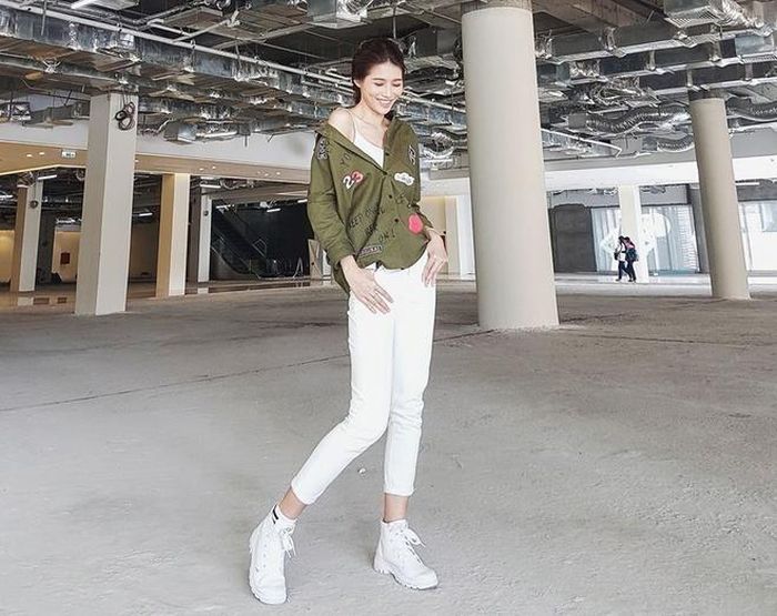 Quỳnh Châu sành điệu trong bộ cánh tông trắng, giày tiệp màu. Áo sơ-mi xanh lục trễ vai tạo sức hút cho set đồ hiện đại.