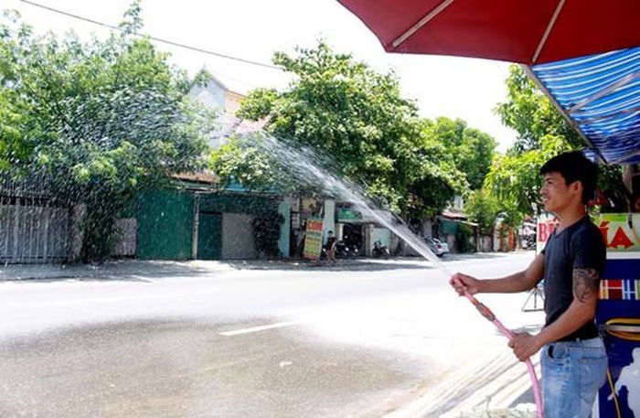 Nhiều người dân ở thành Vinh tăng cường bơm tưới trước cổng nhà để giảm nóng và bụi. Ảnh: Phương Thúy