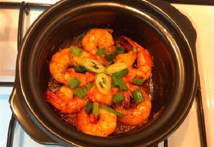 Muốn có nhiều nước để chấm rau hay rưới lên cơm bạn thêm nước và thêm nước mắm, bột nêm nếm sao vừa ăn. Kho với lửa vừa khoảng 5 - 10 phút tùy theo lượng nước trong nồi. Tôm chín bạn nêm nếm lại và thêm tiêu, hành lên mặt. Tắt bếp mang nồi tôm ra, ăn với cơm rau sống, dưa leo cà chua. Ảnh: Cooky.vn.