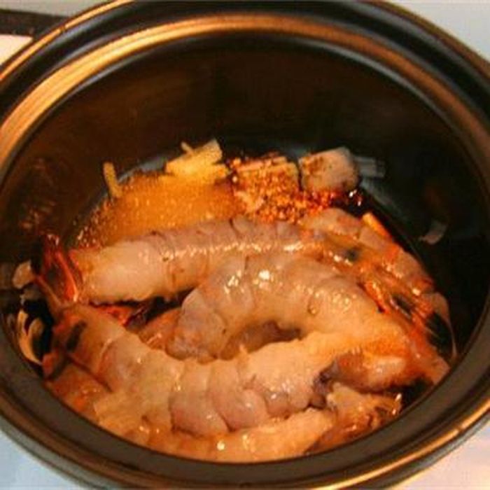 4. Tôm kho nồi đất. Nguyên liệu: Tôm, tỏi, hành tím, dầu ăn, gia vị: nước nắm, bột nêm, đường, tiêu, hành lá. Tôm làm sạch, hành tỏi bằm nhỏ. Phi thơm hành tỏi vào nồi đất. Cho tôm vào xào săn lại, thêm nước mắm, bột nêm, đường, tiêu và nước vừa mặt tôm. Ảnh: Cooky.vn.