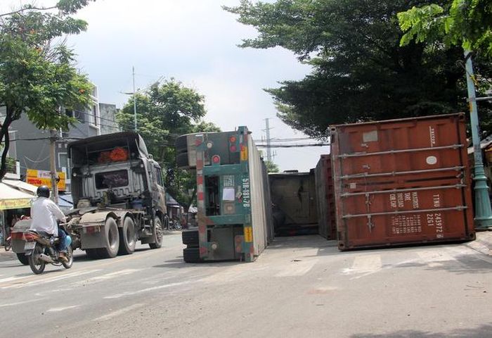 Nhiều người thoát chết khi xe đầu kéo bị lật, cùng thùng container rơi xuống đường. Ảnh: Lê Trai.