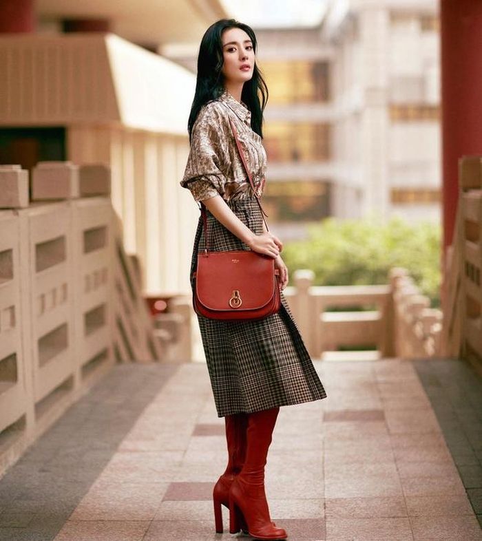 Sành điệu với sơ mi in hoa, chân váy kẻ caro cùng phụ kiện túi xách và bốt cao cổ tông đỏ nổi bật. 