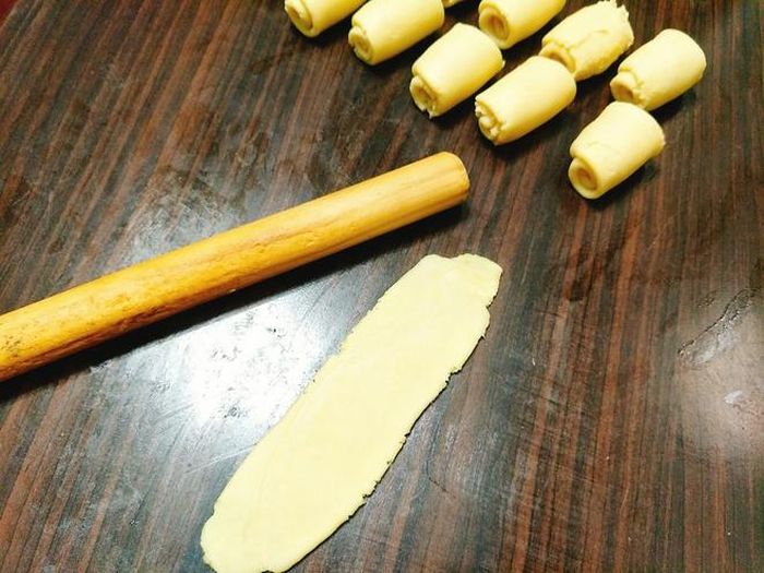 Đặt viên bột vừa gói bột dầu lên bàn, ấn cho hơi dẹt, dùng gậy cán thành miếng bột dài sau đó cuộn từ trên xuống dưới, đậy kín, để bột nghỉ 10 phút. 