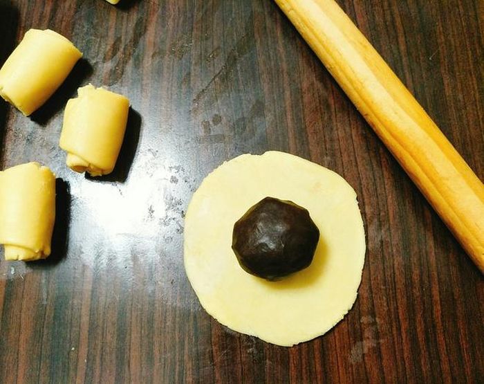 Cán bột thành hình tròn, cho nhân đậu đỏ trứng muối vào giữa, gói bánh cho tròn đều. Sau đó, bạn đặt bánh vào khay nướng và tiếp tục làm cho đến hết. 