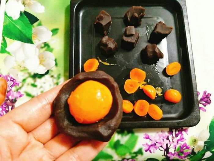 Lấy nhân đậu đỏ, chia đều mỗi miếng 30 g sau đó ấn dẹt và gói nhân trứng muối vào bên trong, vo tròn. 