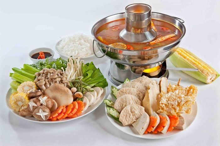 Cho nước dừa tươi vào nồi cùng 1 trái thơm và sả cây đập dập. Tiếp theo cho boa rô cắt khúc và 1 trái bắp cắt khúc vào nồi nước dùng. Cho 2 gói gia vị chua và cay vào nồi nước dùng. Nước dùng sôi, nêm lại cho vừa ăn. Khi ăn múc nước dùng ra nồi nhỏ, cho nấm rơm vào nồi nước dùng cùng cà chua và ngò gai cắt khúc nhỏ. Bày ra rồi trang trí. Ảnh: cachnauan.edu.vn.