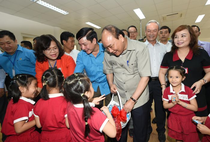 Thủ tướng tặng quà cho các cháu tại khu nhà trẻ dành cho con công nhân. - Ảnh: VGP/Quang Hiếu