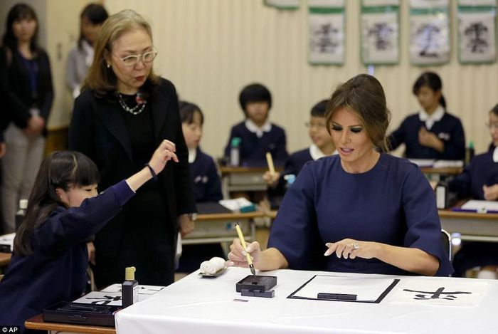 Một bé gái hướng dẫn bà Melania Trump cách chấm mực. Ảnh: AP