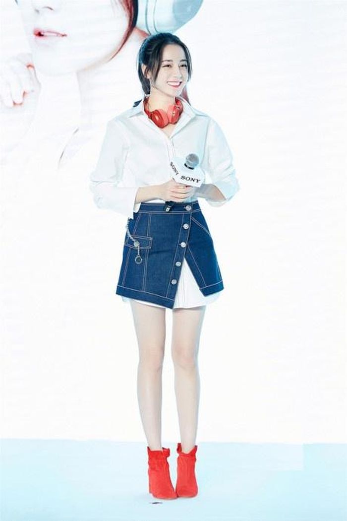 Địch Lê Nhiệt Ba xinh xắn với set đồ cá tính gồm sơ mi oversized dài mix cùng chân váy denim mặc ngoài và bốt đỏ nổi bật.