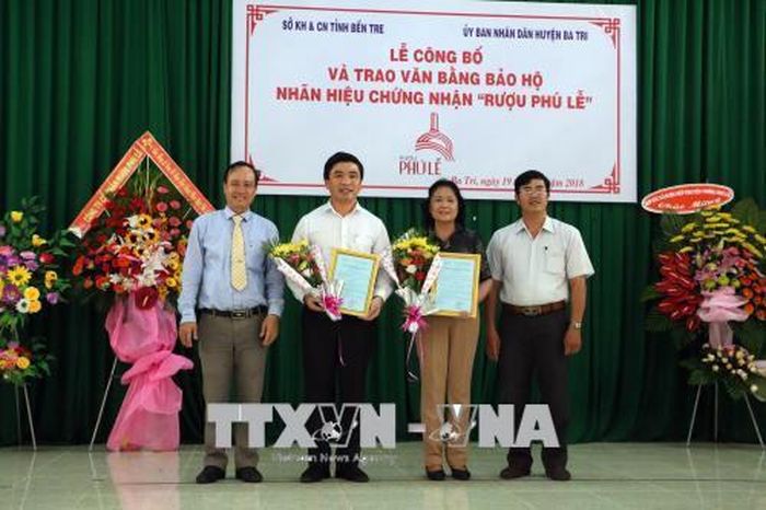  Lãnh đạo UBND huyện Ba Tri trao giấy chứng nhận quyền sử dụng nhãn hiệu "Rượu Phú Lễ" cho các tập thể sản xuất rượu. Ảnh: Trần Thị Thu Hiền - TTXVN